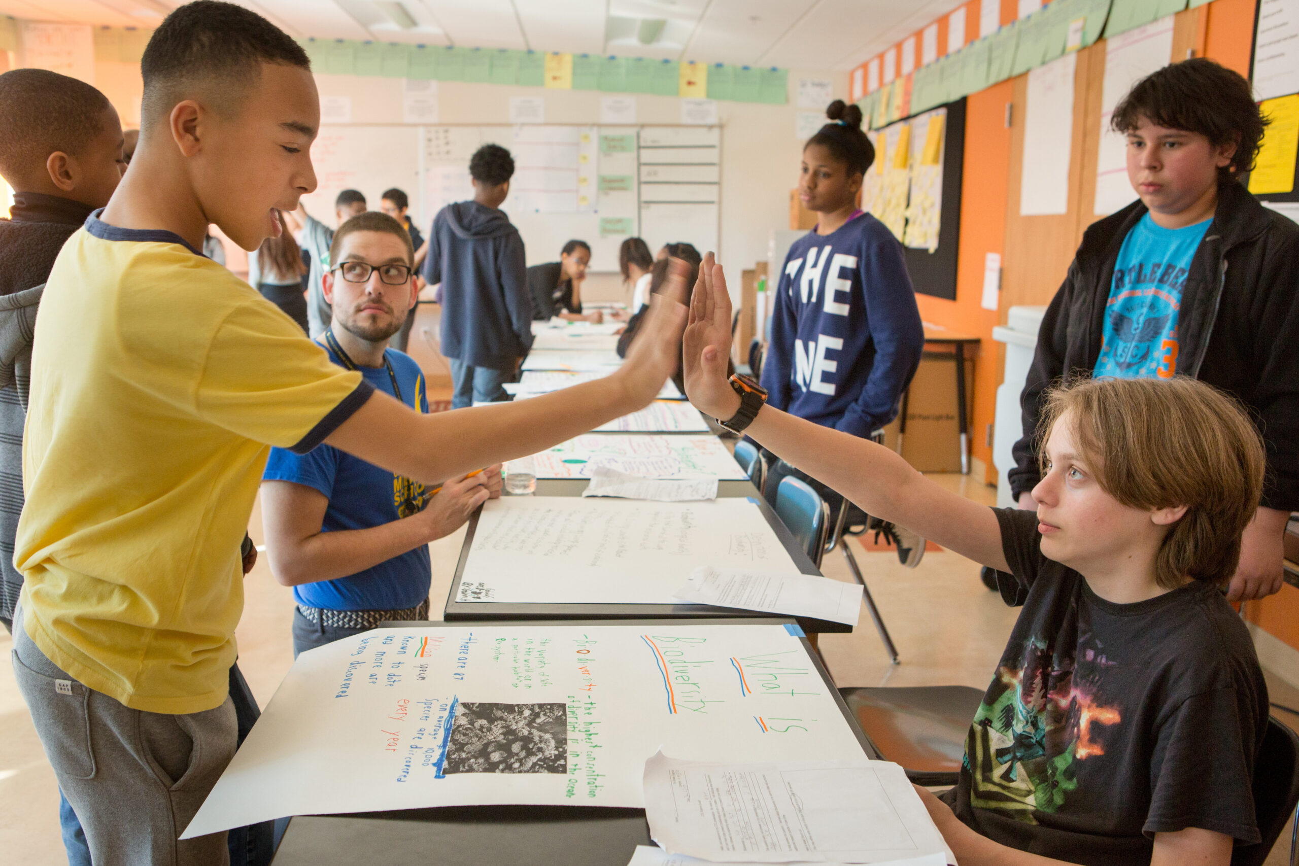 two students high five during a classroom science fair