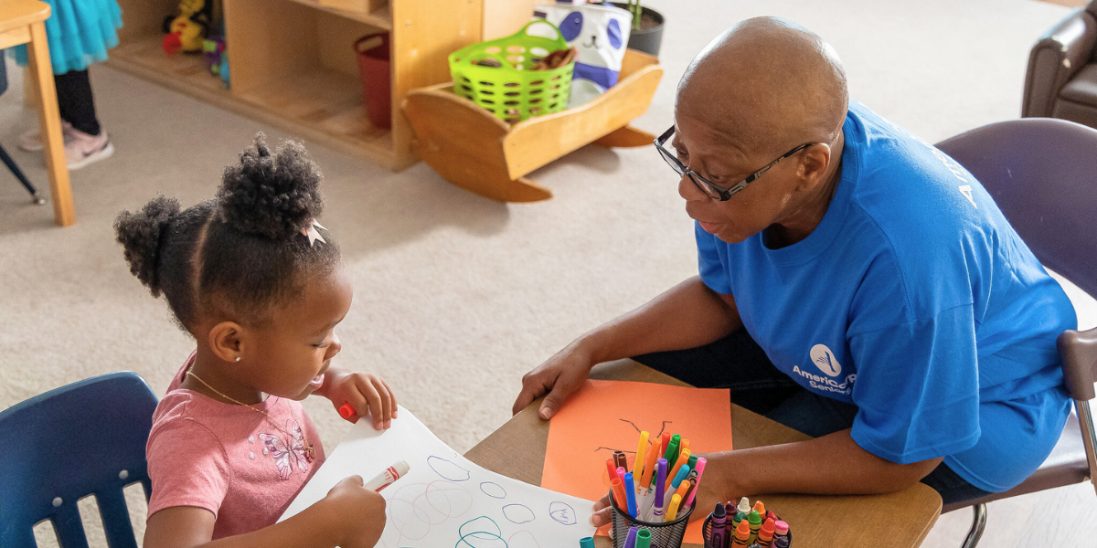 AmeriCorps Mentor Older man helping young girl with school/student support